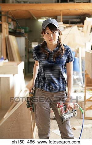 Portrait of a female carpenter holding a drill machine View Large Photo Image Stock Photograph - Portrait of a female carpenter holding a drill machine. Fotosearch
