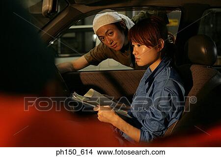 Portrait of a mechanic leaning on a car window with a female mechanic sitting inside a car View Large Photo Image Picture - Portrait of a mechanic leaning on a car window with a female mechanic sitting inside a car. Fotosearch