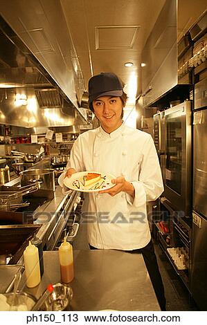 Portrait of a waiter holding a plate of food and standing in the kitchen View Large Photo Image Stock Image - Portrait of a waiter holding a plate of food and standing in the kitchen. Fotosearch