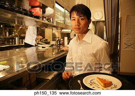 Portrait of a waiter holding a plate of food in the kitchen View Large Photo Image Stock Photography - Portrait of a waiter holding a plate of food in the kitchen. Fotosearch