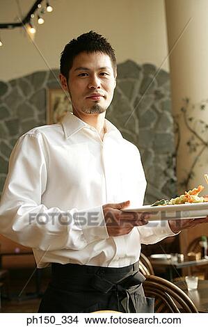 Portrait of a waiter holding a serving tray View Large Photo Image Picture - Portrait of a waiter holding a serving tray. Fotosearch