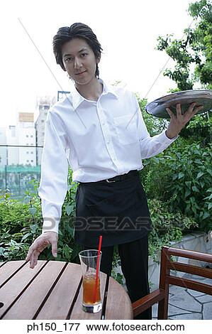 Stock Photo - Portrait of a waiter holding a serving tray. Fotosearch