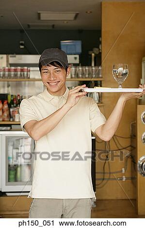 Portrait of a waiter holding a tray with a glass of water and smiling View Large Photo Image Stock Image - Portrait of a waiter holding a tray with a glass of water and smiling. Fotosearch