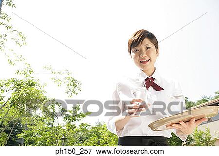 Portrait of a waitress holding two glasses of water and smiling View Large Photo Image Stock Photo - Portrait of a waitress holding two glasses of water and smiling. Fotosearch