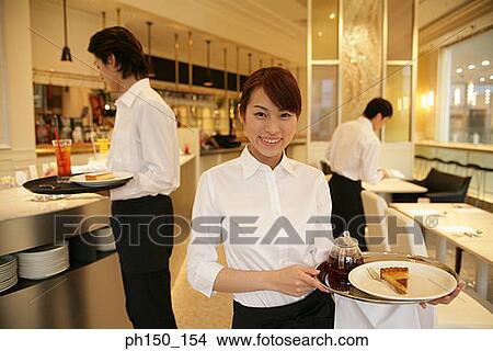 Portrait of a waitress standing in the kitchen with two waiters in the background View Large Photo Image Picture - Portrait of a waitress standing in the kitchen with two waiters in the background. Fotosearch