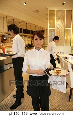 Portrait of a waitress standing in the kitchen with two waiters in the background View Large Photo Image Stock Photograph - Portrait of a waitress standing in the kitchen with two waiters in the background. Fotosearch