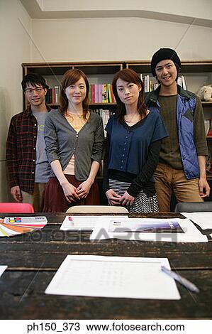 Stock Image - Portrait of two businessmen and two businesswomen standing in an office. Fotosearch