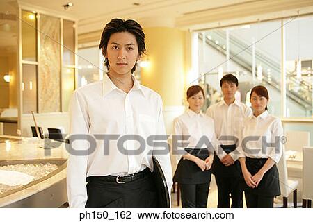 Stock Image - Portrait of two waiters and two waitresses standing in a restaurant. Fotosearch