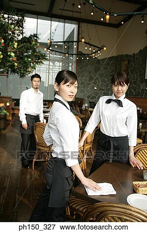 Portrait of two waitresses and a waiter standing in a restaurant View Large Photo Image Stock Photo - Portrait of two waitresses and a waiter standing in a restaurant. Fotosearch