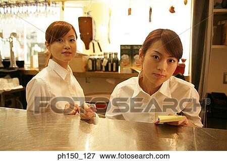 Portrait of two waitresses standing at a kitchen counter View Large Photo Image Stock Photo - Portrait of two waitresses standing at a kitchen counter. Fotosearch