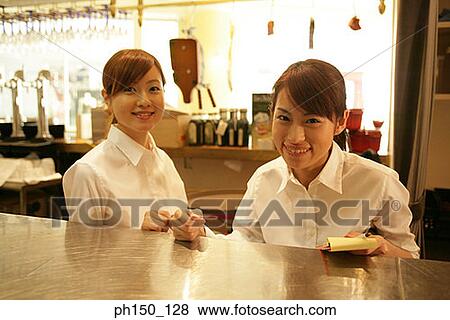 Portrait of two waitresses standing at a kitchen counter and smiling View Large Photo Image Stock Photo - Portrait of two waitresses standing at a kitchen counter and smiling. Fotosearch
