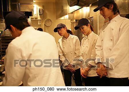 Rear view of a chef preparing food with her colleagues standing beside him View Large Photo Image Stock Image - Rear view of a chef preparing food with her colleagues standing beside him. Fotosearch