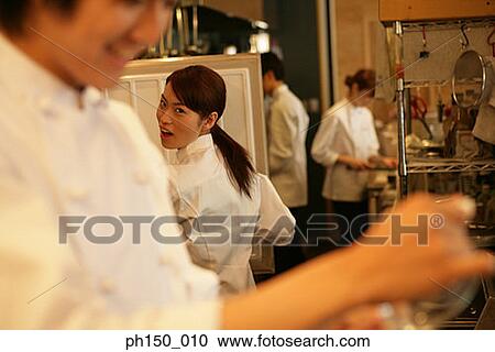 Rear view of a female chef talking to a male chef in the kitchen View Large Photo Image Stock Image - Rear view of a female chef talking to a male chef in the kitchen. Fotosearch