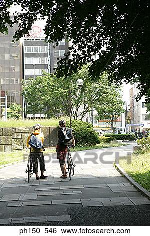 Rear view of a man and a woman standing with bicycles View Large Photo Image Stock Photograph - Rear view of a man and a woman standing with bicycles. Fotosearch