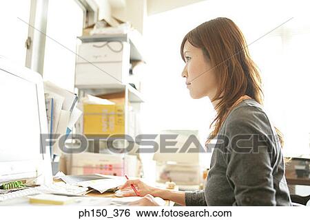 Stock Photograph - Side profile of a businesswoman working on a computer. Fotosearch