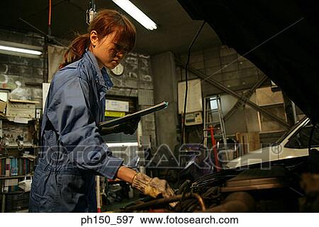 Side profile of a female auto mechanic repairing an engine View Large Photo Image Stock Photo - Side profile of a female auto mechanic repairing an engine. Fotosearch