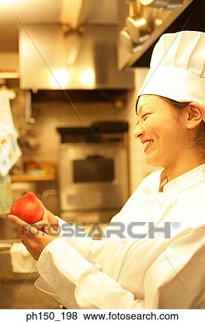 Side profile of a female chef holding a tomato and smiling View Large Photo Image Stock Photo - Side profile of a female chef holding a tomato and smiling. Fotosearch