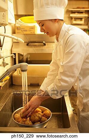 Side profile of a female chef washing raw potatoes in the kitchen sink View Large Photo Image Stock Photo - Side profile of a female chef washing raw potatoes in the kitchen sink. Fotosearch