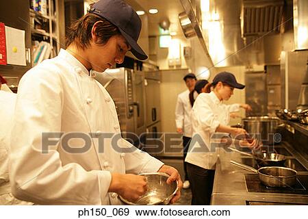 Side profile of a male chef and his colleagues in the kitchen View Large Photo Image Stock Photo - Side profile of a male chef and his colleagues in the kitchen. Fotosearch