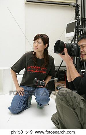 Side profile of a photographer taking a photograph with a young woman kneeling beside him View Large Photo Image Stock Photo - Side profile of a photographer taking a photograph with a young woman kneeling beside him. Fotosearch