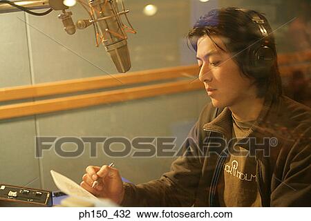 Stock Image - Side profile of a young man recording music in a recording studio. Fotosearch