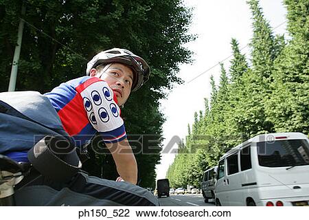 Stock Image - Side profile of a young man wearing a cycling helmet. Fotosearch