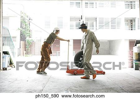 Side profile of an auto mechanic holding a tire with a mechanic pushing a car jack View Large Photo Image Stock Image - Side profile of an auto mechanic holding a tire with a mechanic pushing a car jack. Fotosearch