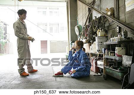 Side profile of two auto mechanics talking in an auto repair shop View Large Photo Image Stock Photo - Side profile of two auto mechanics talking in an auto repair shop. Fotosearch