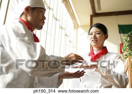 Two chefs standing in a restaurant and discussing View Large Photo Image Picture - Two chefs standing in a restaurant and discussing. Fotosearch