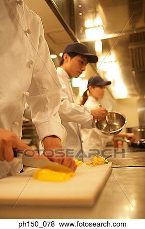 Two male chefs and a female chef preparing food in the kitchen View Large Photo Image Stock Photo - Two male chefs and a female chef preparing food in the kitchen. Fotosearch