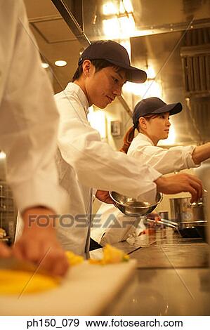 Two male chefs and a female chef preparing food in the kitchen View Large Photo Image Stock Photo - Two male chefs and a female chef preparing food in the kitchen. Fotosearch