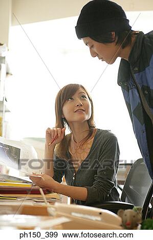 Two office workers discussing in an office View Large Photo Image Stock Photo - Two office workers discussing in an office. Fotosearch