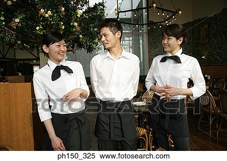 Two waitresses with a waiter standing in a restaurant and smiling View Large Photo Image Stock Photography - Two waitresses with a waiter standing in a restaurant and smiling. Fotosearch