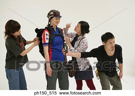 Stock Photography - Two young women and a young man assisting a female fashion model at a photo shoot. Fotosearch