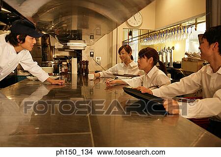 Waiters standing at a kitchen counter and talking to a chef View Large Photo Image Picture - Waiters standing at a kitchen counter and talking to a chef. Fotosearch