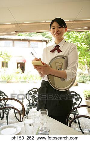 Stock Image - Waitress writing on a notepad and smiling. Fotosearch