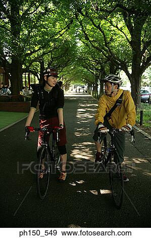 Stock Photo - Young couple riding bicycles and looking at each other. Fotosearch