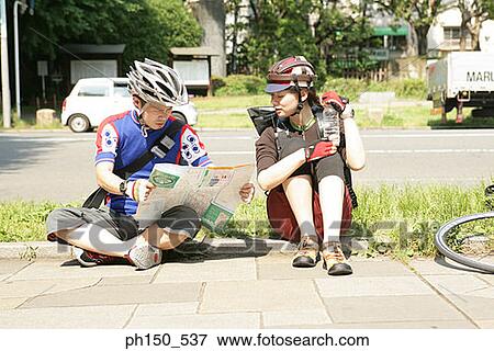 Young couple sitting at the roadside and looking at a road map View Large Photo Image Stock Photo - Young couple sitting at the roadside and looking at a road map. Fotosearch