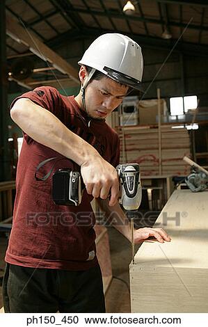 Young man drilling a hole in wood View Large Photo Image Stock Image - Young man drilling a hole in wood. Fotosearch