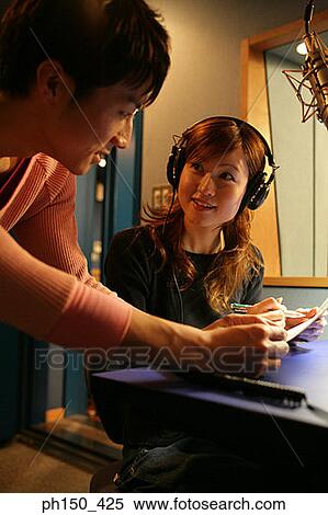 Young woman and a young man discussing a document in a music studio View Large Photo Image Stock Photography - Young woman and a young man discussing a document in a music studio. Fotosearch