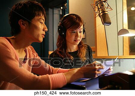 Young woman and a young man looking at a sheet of paper in a music studio View Large Photo Image Picture - Young woman and a young man looking at a sheet of paper in a music studio. Fotosearch