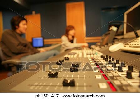 Stock Photo - Young woman and a young man sitting in a recording studio. Fotosearch