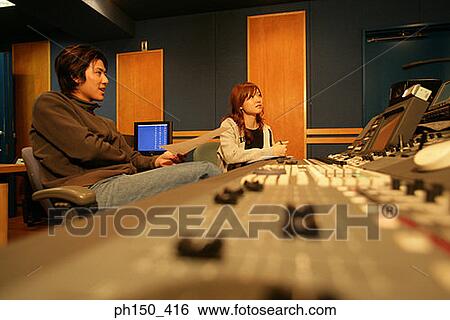 Young woman and a young man sitting in a recording studio View Large Photo Image Stock Photograph - Young woman and a young man sitting in a recording studio. Fotosearch