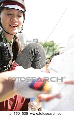 Stock Photography - Young woman looking at a road map and smiling. Fotosearch