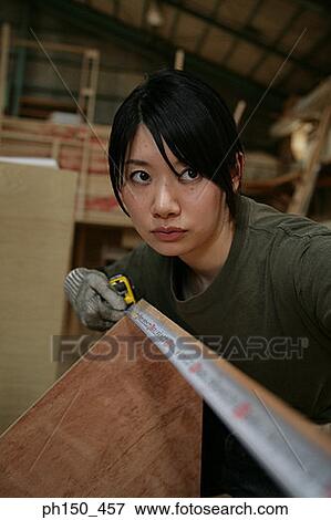 Young woman measuring a sheet of plywood with a tape measure View Large Photo Image Stock Photo - Young woman measuring a sheet of plywood with a tape measure. Fotosearch
