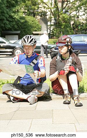 Young woman sitting with a young man reading a road map View Large Photo Image Stock Photograph - Young woman sitting with a young man reading a road map. Fotosearch
