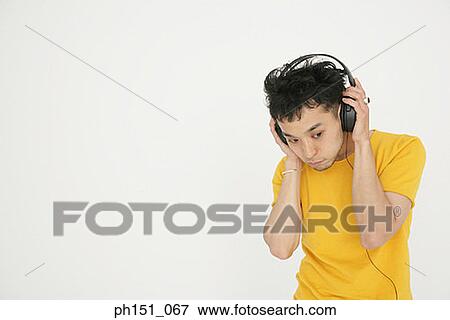 Close-up of a young man wearing headphones and listening to music View Large Photo Image Stock Photo - Close-up of a young man wearing headphones and listening to music. Fotosearch