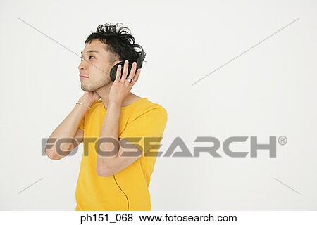Stock Photo - Close-up of a young man wearing headphones and listening to music. Fotosearch