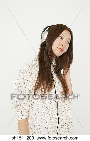 Stock Image - Close-up of a young woman listening to music on headphones. Fotosearch