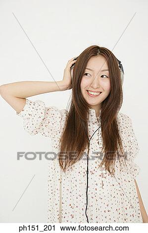 Close-up of a young woman listening to music on headphones View Large Photo Image Stock Image - Close-up of a young woman listening to music on headphones. Fotosearch